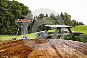 Tabletop and blurred grill on grass and garden background.