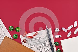 Tabletop role playing flat lay with RPG game dices, hand drawn dungeon map, rule books and pen at bottom of red background photo