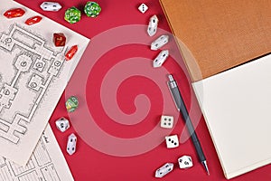 Tabletop role playing flat lay with RPG game dices, hand drawn dungeon map, rule books and pen on red background