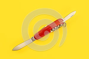Tabletop view, red pocket knife, with both blades opened, laying on yellow board