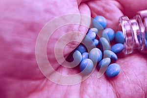 Tablets amphetamines poured from a glass container in hand close-up macro