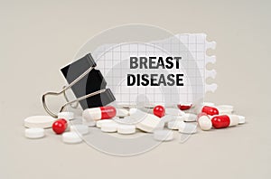 Among the tablets and capsules is a clip with paper on which is written - BREAST DISEASE