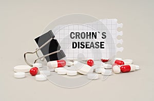 Among the tablets and capsules is a clip with paper on which is written - CROHNS DISEASE photo