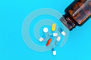 Tablets, capsules pills and tablets spilling out of a drug bottle.