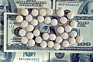 Tablets on dollar bills (treatment, addiction, aging - concept). Vintage effect.