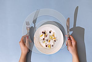 Tablets, pills and capsules on a white porcelain plate. The table is set with a plate