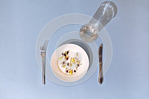 Tablets, pills and capsules on a white porcelain plate. The table is set with a plate