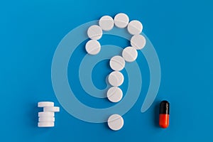 The tablets are white meds on a blue background. A symbol of a question mark. Choose between multiple pills and medical pills