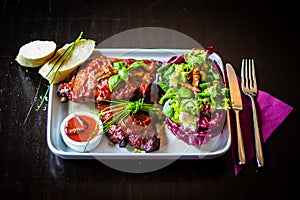 Tableview of spareribs with salad, chili sauce and baguette on w