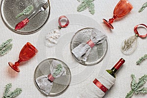 Tableware for Christmas or Xmas festive dinner, linen napkin on plate, knife, fork, red wine glass, bottle of wine on