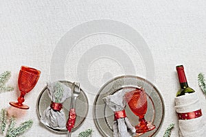 Tableware for Christmas or Xmas festive dinner, linen napkin on plate, knife, fork, red wine glass, bottle of wine on
