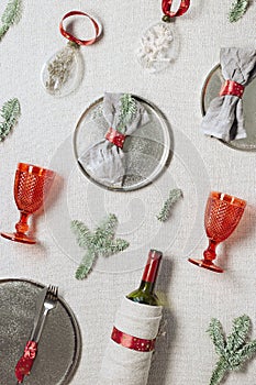 Tableware for Christmas or Xmas festive dinner, linen napkin on plate, red wine glass, bottle of wine on rustic