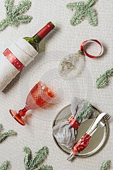 Tableware for Christmas or Xmas festive dinner, linen napkin on plate, red wine glass, bottle of wine on rustic