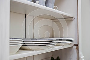 Tableware on a wooden shelf, plates and cups in a closet