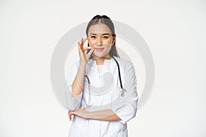 Taboo, medical confidentiality concept. Young asian doctor, female physician showing mouth silence, taboo or zip gesture