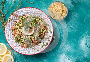 Tabule - an oriental salad, an appetizer on a blue background next to a lemon and bulgur photo