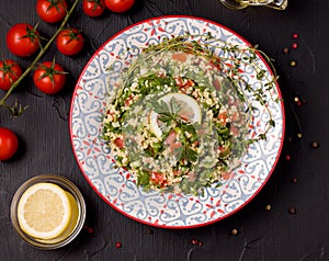 Tabule - oriental salad, close to the ingredients and on a black table photo