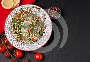 Tabule salad on a black background next to the ingredients photo