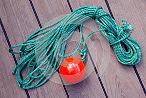 tackle to facilitate the supply of the mooring cable to the shore. A coil of thin green rope with a plastic red ball on the end.