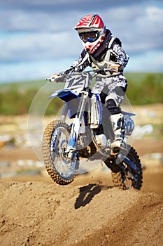 Tackling each obstacle as they come along. A motocross rider doing a small jump.