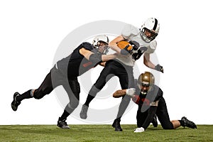 Tackling. Three young sportive men, professional american football players in sports uniform and equipment in action