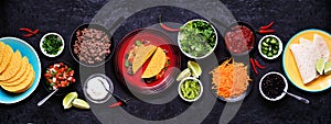 Taco bar table scene with a selection of ingredients on a dark slate banner background