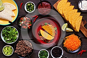 Taco bar table scene with a selection of ingredients on a dark wood background