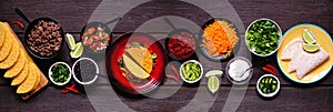 Taco bar table scene with a selection of ingredients on a dark wooden banner