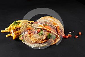 Tacos with chicken, tomato and fresh vegetables and tartar sauce on black background