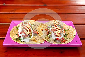 Tacos. Handmade Mexican food served in a pink plate placed on a wooden surface. Authentic Spicy Food