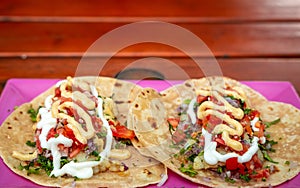 Tacos. Handmade Mexican food served in a pink plate placed on a wooden surface. Authentic Spicy Food