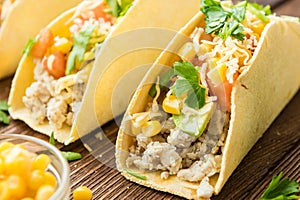 Tacos with lime, corn, chicken, tomato, avocado, cheese and parsley