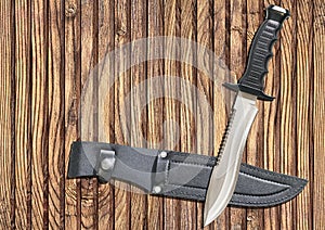 Tactical Combat Hunting Survival Sawback Bowie Knife With Black Leather Sheath On Old Knotted Pinewood Background