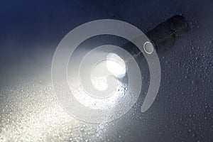 Tactical flashlight on wet surface with beam