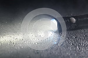 Tactical flashlight on wet surface with beam