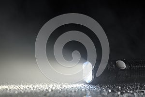 Tactical waterproof flashlight on wet surface