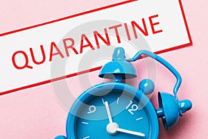 Tag with text and alarm clock on pink background. Concept of the time action of the introduced quarantine