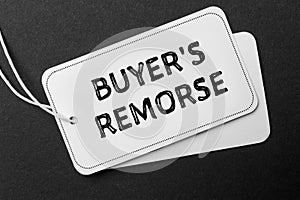 Tag with text Buyer\'s Remorse on black background, top view photo
