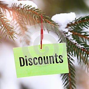 Tag with text hanging on a fir branch, concept on the theme of winter discounts