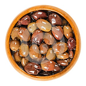Pitted Taggiasca olives in wooden bowl over white photo