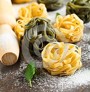 Tagliatelle Paglia e Fieno. on a dark background. Making homemade pasta linguine on rustic kitchen table with flour, rolling pin photo