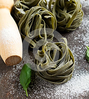 Tagliatelle Paglia e Fieno. on a dark background. Making homemade pasta linguine on rustic kitchen table with flour, rolling pin photo