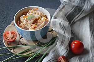 Tagliatelle pasta with shrimps and tomato sauce on dark background. Italian cuisine.