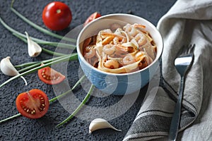 Tagliatelle pasta with shrimps and tomato sauce on dark background. Italian cuisine.