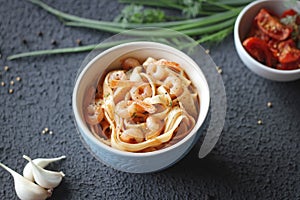 Tagliatelle pasta with shrimps and tomato sauce dark background. Italian cuisine