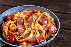 Tagliatelle pasta with tomato sauce parmesan basil on rustic background