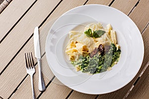 Tagliatelle vegetarian Pasta Dish with spinach and dried tomatoes decorated with basil. Delicious lunch with pasta and