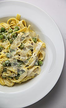 Tagliatelli con Limone e Piselli on white plate corner view photo