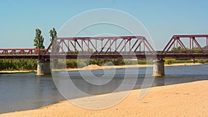 The tagus river and a red steel bridge, Coruche, Portugal