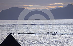 Tahiti. Silhouettes of boats with rowers at sunset in the sea.